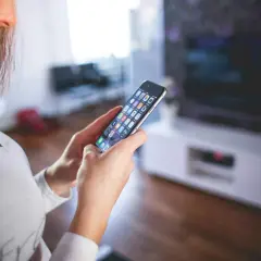 Kobieta steruje inteligentnym domem przez aplikację na smartfonie. Czy to smart life, czy Tuya?