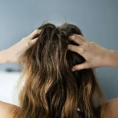Manos rascando el cuero cabelludo, con el pelo roto por arriba.