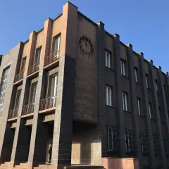 Monumentalny budynek z zegarem, przykład art deco w Polsce. Geometryczne formy, ciemna i jasna elewacja, wąskie okna.