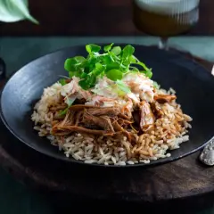 En tallrik med pulled pork med ris, toppad med en krispig coleslaw och färska örter. En härlig måltid!