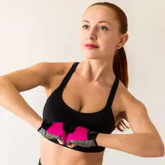 Kobieta w sportowym topie i rękawiczkach ćwiczy, by jak podnieść piersi.