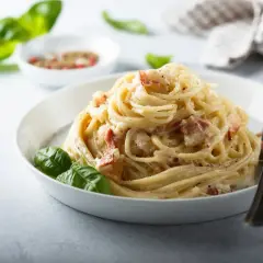 Pyszne spaghetti carbonara z boczkiem i bazylią. Idealne carbonara skladniki na szybki obiad.