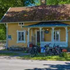 Gult hus med café & vandrarhem. Cyklar står parkerade framför. Folk sitter vid bord utomhus.