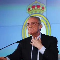 Florentino Pérez, prezes Realu Madryt, w garniturze i okularach, przemawia na tle klubowego logo.