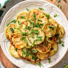 Fette di zucchine dorate e profumate, un'idea per una ricetta zucchine light veloci e gustosa, guarnite con prezzemolo fresco.