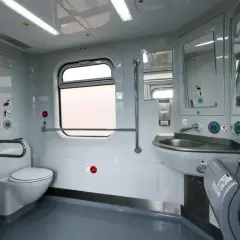 Wnętrze toalety w pociągu Pendolino: biała muszla klozetowa, umywalka, lustro, suszarka do rąk i okno.