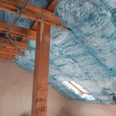 Piana na poddasze tworzy izolacyjną warstwę na drewnianej konstrukcji dachu, z widocznym oknem dachowym.