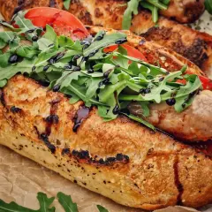 Ein knuspriges Baguette mit einer herzhaften salsiccia italiana, frischen Tomaten und Rucola, beträufelt mit Balsamico.