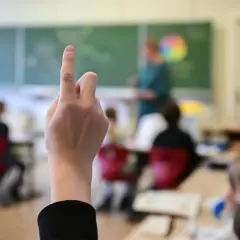 Ein Schüler hebt die Hand im Unterricht. Seit wann gibt es die Schulpflicht in Deutschland? Die Antwort liegt im Dunkel der Geschichte, aber die heutige Schulpflicht ist ein Meilenstein.