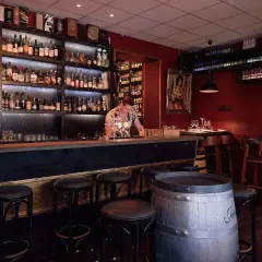 En bar med hyllor fyllda med flaskor, en bardisk med pallar och en bartender. En perfekt plats för vinbarer Stockholm.