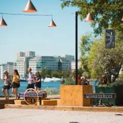 Vänner njuter av utomhusaktiviteter i Stockholm vid vattnet, med spel och stadens silhuett i bakgrunden.