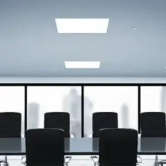 Sala de juntas moderna con mesa y sillas negras, iluminada por un panel led techo.
