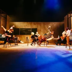 Aktorzy Teatru Lalek Pleciuga w dynamicznych pozach na scenie, unoszący się w powietrzu.