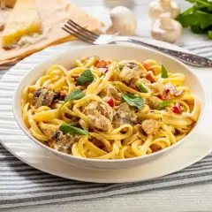 Un plat de pâtes crémeuses, un délice "one pot pasta" avec poulet, champignons et herbes fraîches.