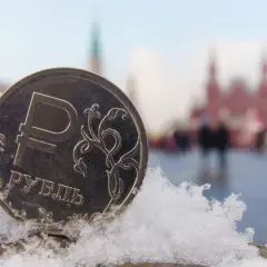 Moneta z symbolem rubla, wskazująca, jaka waluta obowiązuje w Rosji, na tle ośnieżonego placu Czerwonego.