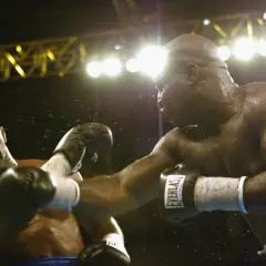 Two boxers clash under bright lights. The sound of their punches echoes, a testament to the force behind each blow.