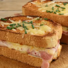 Deux croque monsieur bistrot, dorés et gratinés, garnis de jambon et fromage fondant, parsemés de ciboulette fraîche.