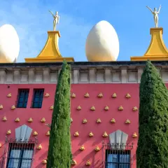 Dach budynku w stylu surrealistycznym, ozdobiony jajami i figurami, przypomina dzieła hiszpańskich malarzy.