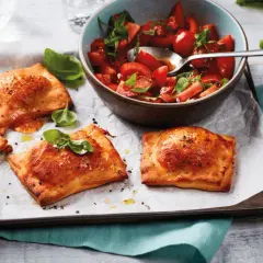 Goldbraune Teigtaschen, gefüllt und gebacken, zeigen, was man aus pizzateig machen kann. Dazu ein frischer Tomatensalat.