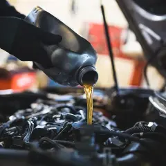 Mano con guanto versa olio motore. Un'operazione di cambio olio per un cambio manuale.