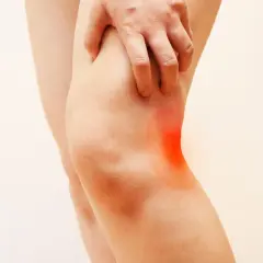 Dolore dietro al ginocchio quando cammino, evidenziato da un'area rossa. La mano stringe il ginocchio.