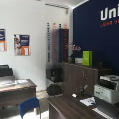 Biuro firmy ubezpieczeniowej Unilink z plakatami, drukarką i meblami.