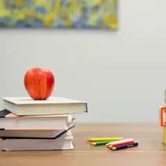 Stapel boeken met appel, potloden en ABC-blokken. Een visuele weergave van verschillende lees niveaus, van beginners tot gevorderden.