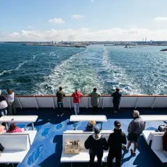Ludzie na pokładzie promu do Ystad podziwiają widok na morze i oddalające się wybrzeże.