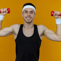 Ein Mann mit Stirnband und Schweißbändern macht Unterarmtraining mit roten Hanteln.