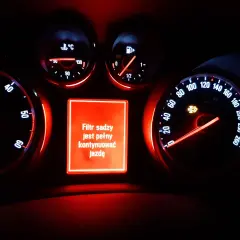 Na desce rozdzielczej Opla świeci się czerwona kontrolka dpf, informując o zapchanym filtrze cząstek stałych i konieczności kontynuowania jazdy.
