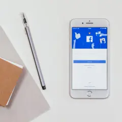 Telefon z ekranem logowania Facebooka. Obok notatnik i długopis. Jak sprawdzić hasło na FB będąc zalogowanym?