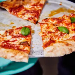 Une pizza diabola appétissante, avec sa croûte dorée, sa sauce tomate épicée et son fromage fondant, garnie de feuilles de basilic frais.