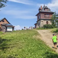 Rodzina wędruje szlakiem luboń wielki szlak niebieski. W tle schronisko i wieża widokowa.