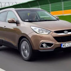 Brązowy Hyundai ix35 w ruchu drogowym, z widocznym kierowcą.