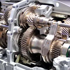 Widok przekładni wewnątrz skrzyni biegów manualnej. Metalowe koła zębate i wałki tworzą skomplikowany mechanizm.
