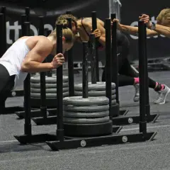 Frauen beim intensiven Hyrox Training schieben schwere Schlitten.
