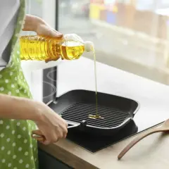 En person häller vegetabilisk olja i en grillpanna.