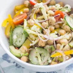 Salade de pois chiches colorée avec concombre, poivron jaune, tomate et feta dans un bol blanc.