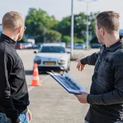 Egzaminator wskazuje na plan placu manewrowego, omawiając jak wygląda egzamin praktyczny kat B.