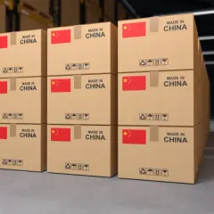 Stosy kartonów z napisem "MADE IN CHINA" i flagą Chin, gotowe do wysyłki. Każdy karton ma symbole ostrzegawcze, jak przy transporcie morskim, co może być podstawą do wystawienia konosamentu.