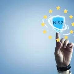 Palec wskazujący dotyka tarczy z napisem NIS2, otoczonej gwiazdkami Unii Europejskiej. Symbolizuje to bezpieczeństwo i zgodność z dyrektywą NIS2.