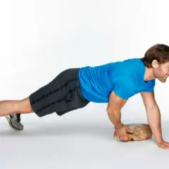 Man performing an around the world plank exercise, balancing on one hand and a paper bag.
