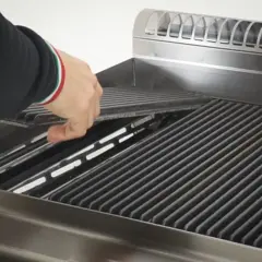 Mano che posiziona le pietre laviche nel barbecue a gas, pronte per una grigliata perfetta.
