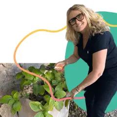 Une femme souriante jardine, un exemple de loisirs pour jeunes retraités actifs et épanouis.