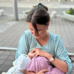 Mama karmi piersią dziecko na ławce w parku. Naturalne karmienie piersią w miejscu publicznym to piękny widok.