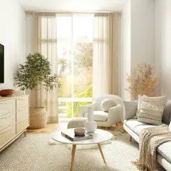 Salon cosy et chic avec canapé, fauteuil, table basse, commode en bois, plante verte et miroir rond en rotin. Parfait pour une deco salon cocooning chic.
