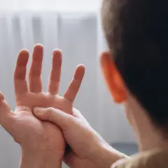 Mężczyzna masuje dłoń, odczuwając drętwienie rąk.