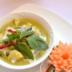 Zielony curry z kurczakiem, mleczkiem kokosowym i bazylią. Czy przyprawa curry jest ostra? Ten talerz sugeruje, że tak, dzięki czerwonym papryczkom chili.
