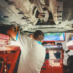 Mechanik pracuje pod samochodem, sprawdzając sworzeń wahacza.