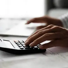 Ręce liczą na kalkulatorze, przygotowując dokumenty do wniosku o zwrot prowizji kredyt hipoteczny. UOKiK może pomóc.
